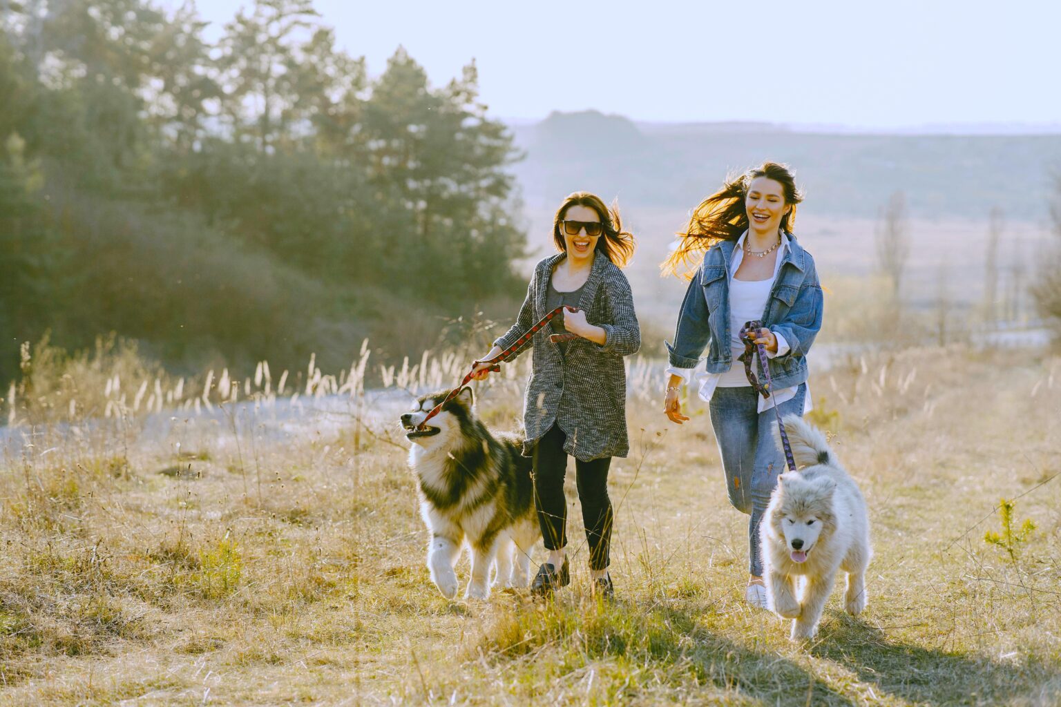 Two happy women running with their two dogs